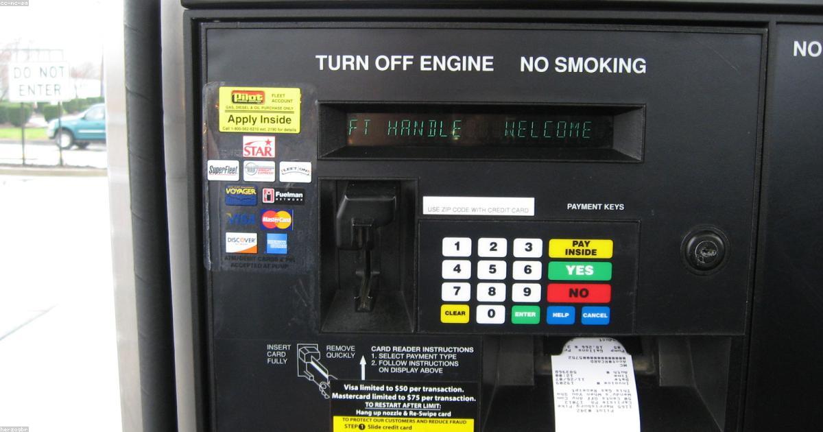 Pessoa abastecendo carro em posto de gasolina e usando cartão de crédito no aplicativo