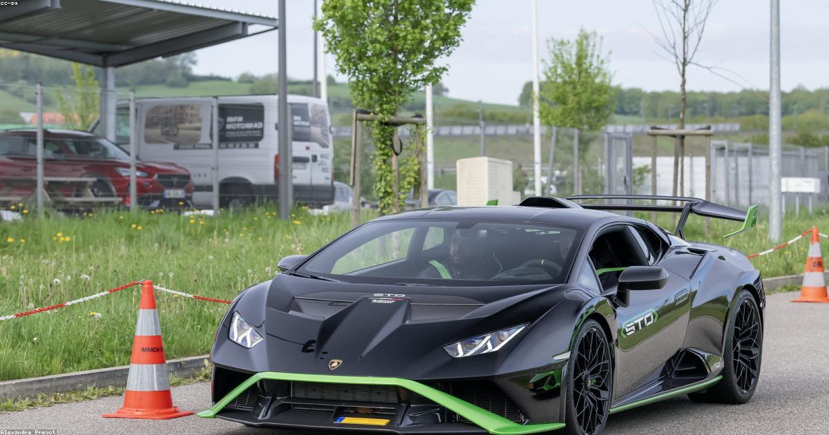 Quatro SUVs e sedãs de luxo enfileirados em frente a edifício moderno