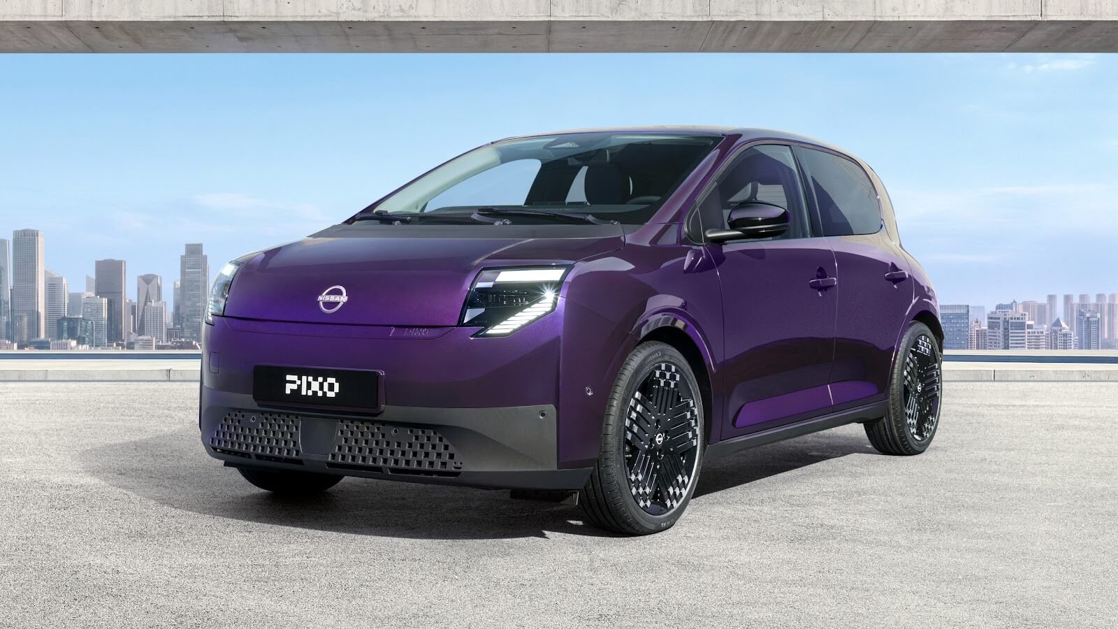 Three-quarter front view of a purple Nissan PIXO electric city car parked beneath a modern concrete structure, with a city skyline in the background.